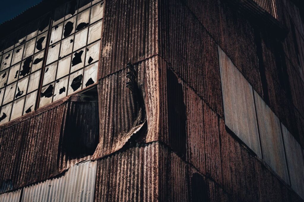 A close-up view of a rusty and decaying building facade with broken windows, showcasing urban decay.