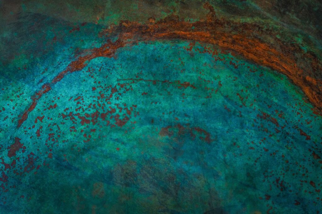 Close-up abstract of weathered metal surface with turquoise patina and rust details.